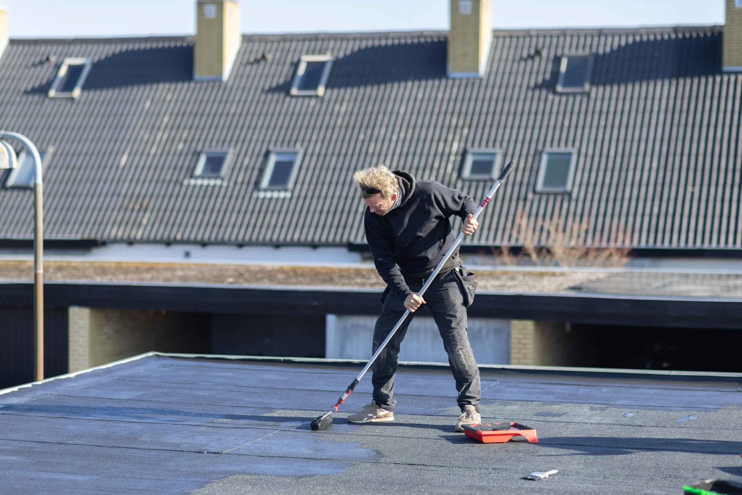 Klimacoating – montør påfører primer på tagflade med rulle